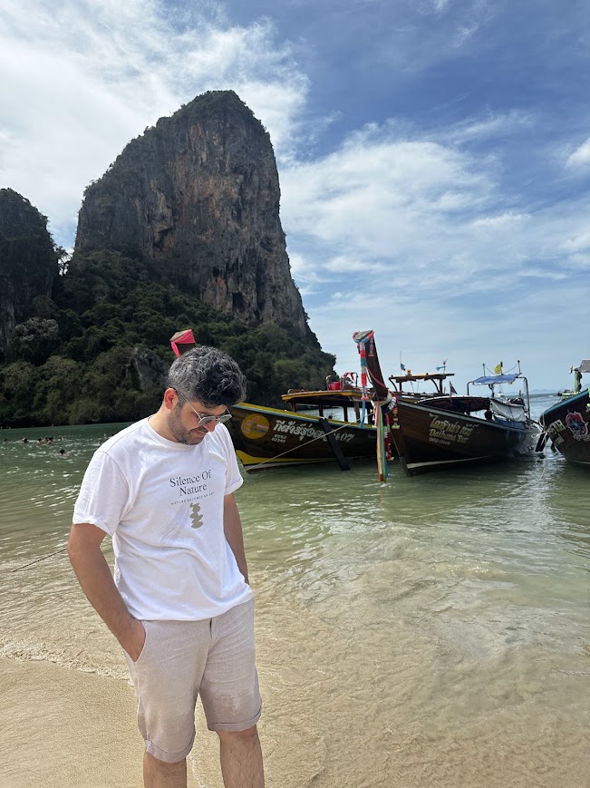 Railay plajında longtail tekneler ve arkadaki dev kireçtaşı falez